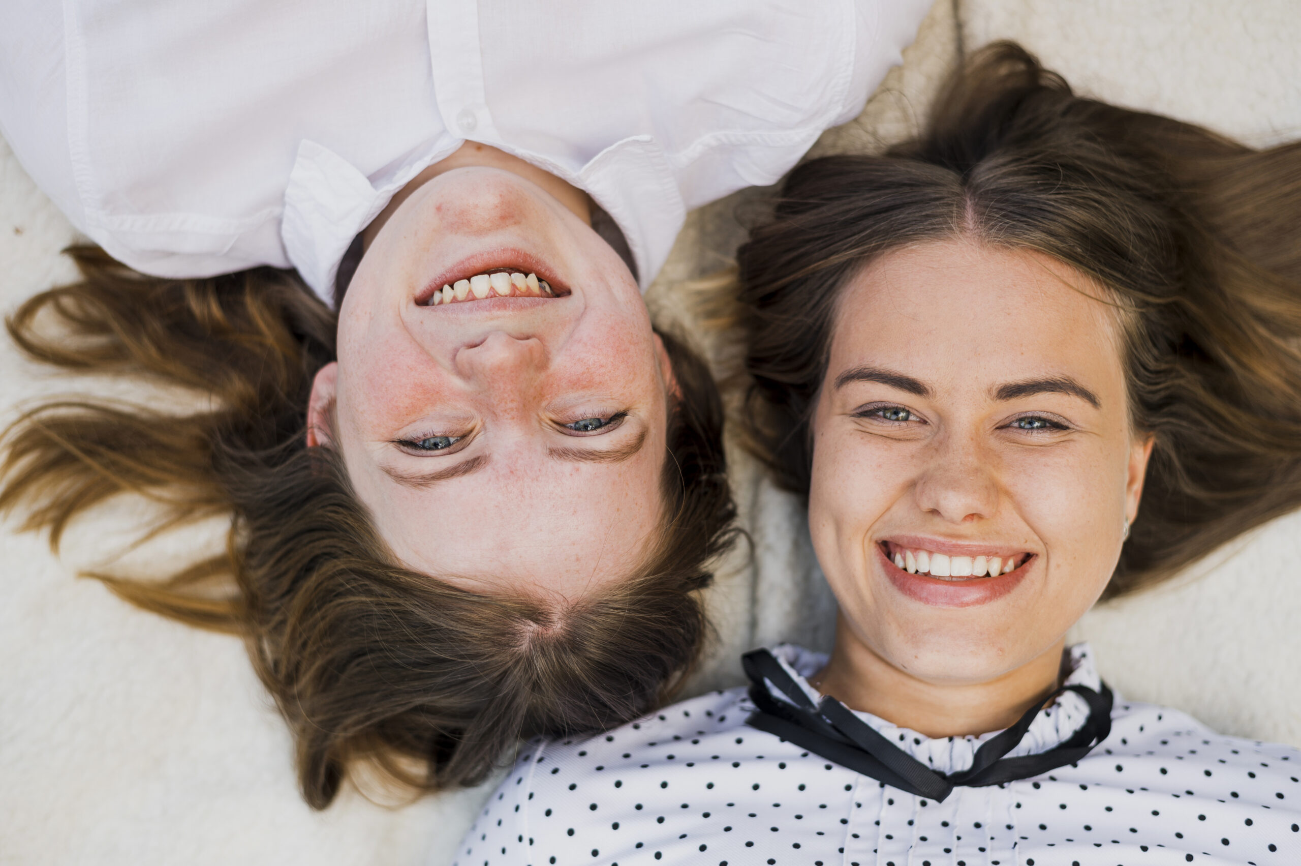 A group of smiling teenagers looking up at the camera from a top view, showcasing diverse expressions of joy and friendship.